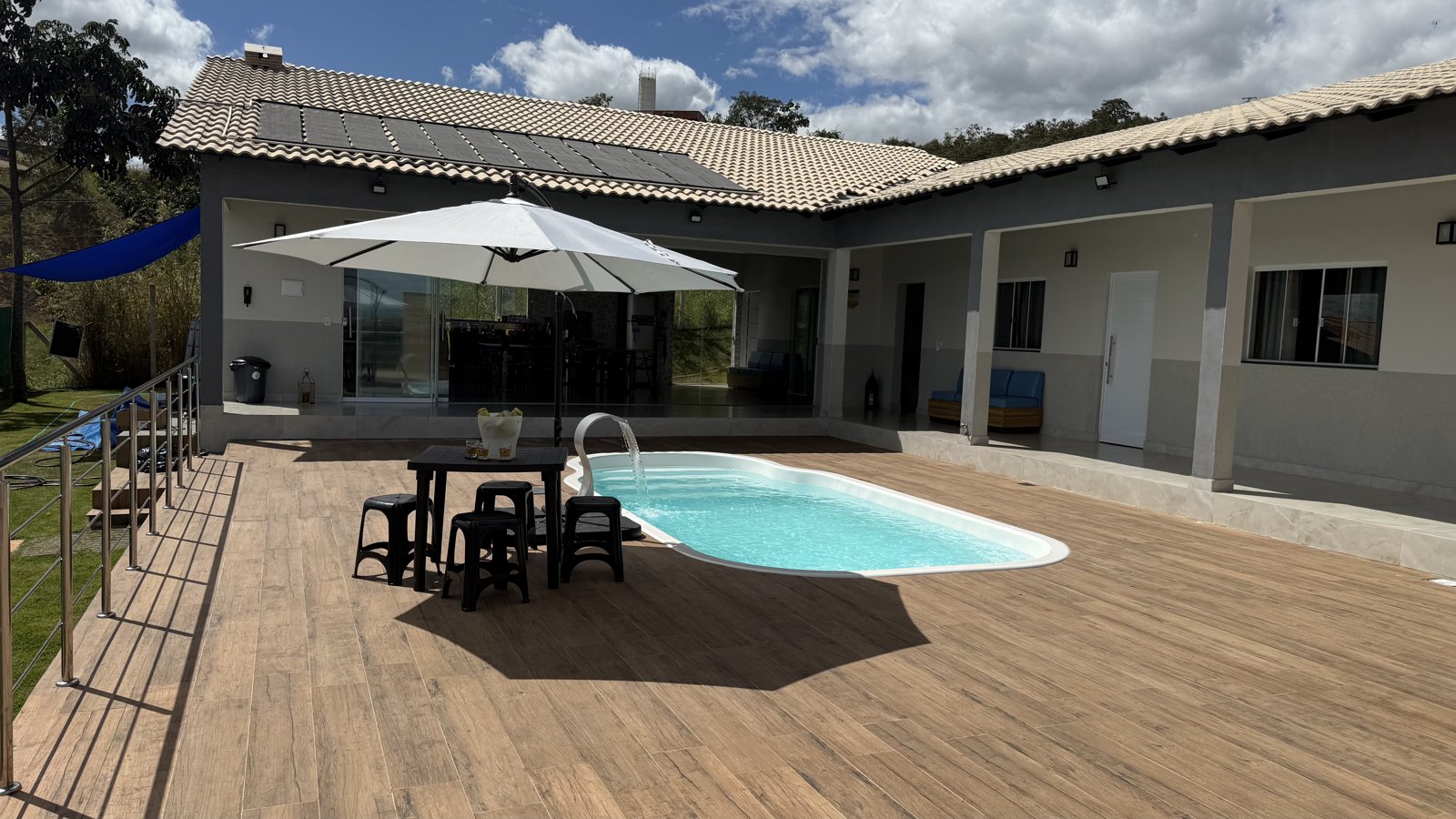 Área da piscina com deck e ombrelone